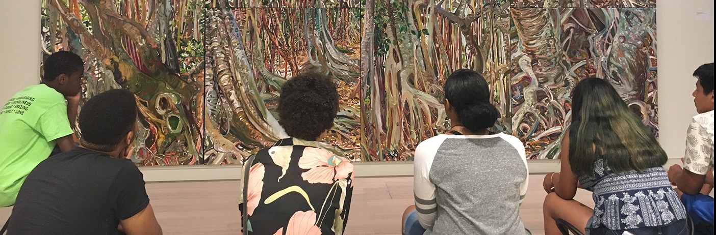 A school visit group sits on a bench viewing art in the Wallach Art Gallery