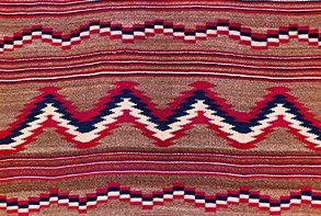 Child's banket (detail), 1879-80 by an Unknown Diné (Navajo) maker Unknown Diné (Navajo) maker, Child's banket (detail), 1879-80. Collection of Art Properties, Avery Architectural & Fine Arts Library. This woven textile includes horizontal sections of alternating zig-zag patterns and stripes in red, white, and dark blue on a tan colored background