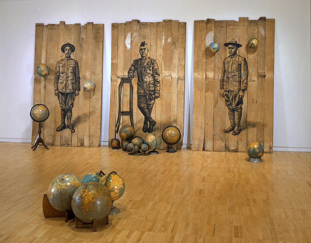 Whitfield Lovell. "Autour Du Monde," 2008. Conte crayon on wood panel with globes; 102 x 189 x 171 in. Courtesy the artist and DC Moore Gallery, New York.