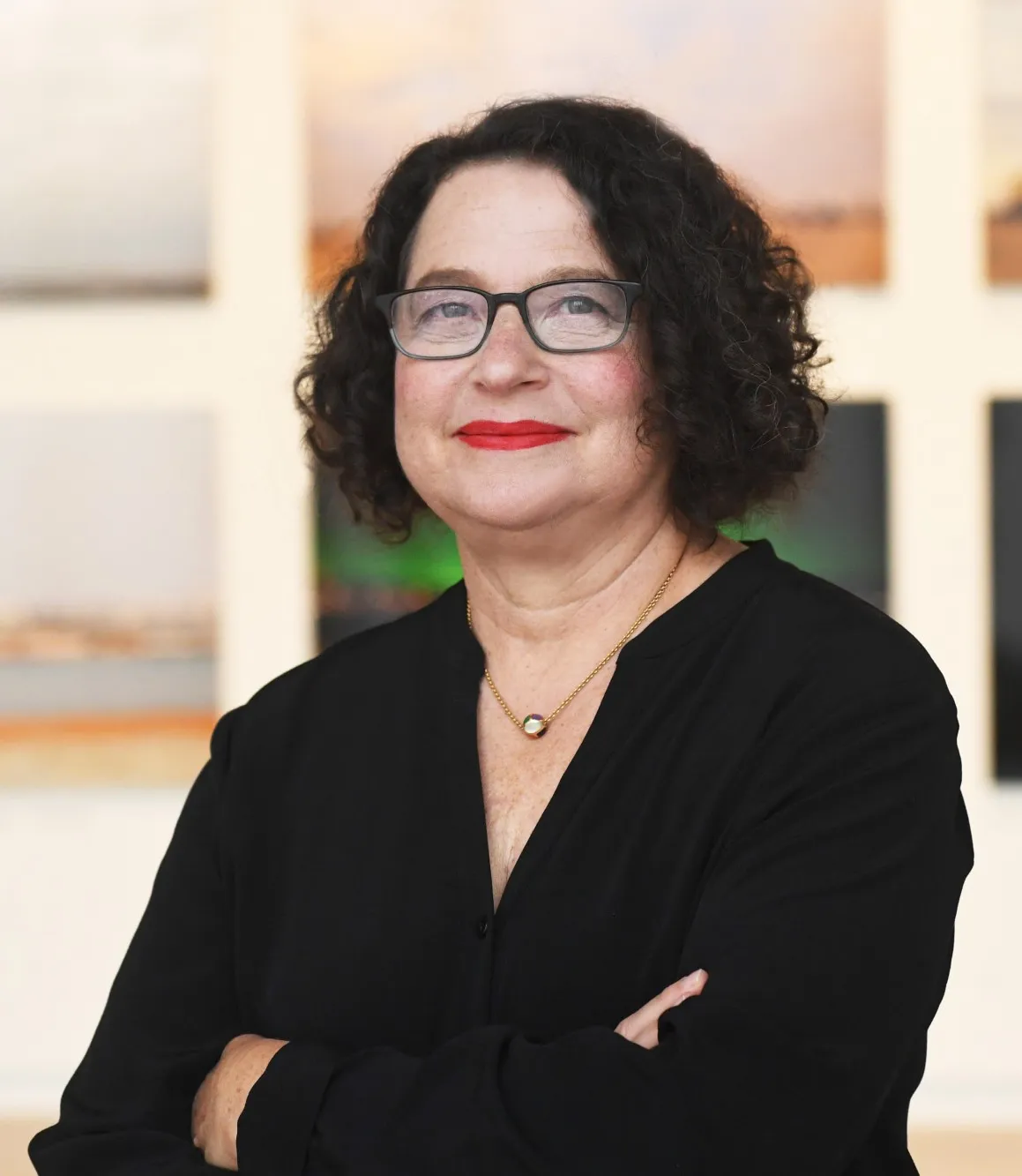 Bust-portrait of Betti-Sue Hertz standing in front of photographs in the Wallach Art Galler