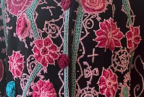 Milagros Batista, detail of "Sikolo the Beautiful," 2023. Mixed media, hand-crocheted floral motifs and embroidery on an upcycled coat, 40 x 20 x 10 inches (variable when worn).