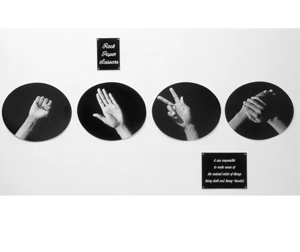 Lorna Simpson, Plaques, 1986. 4 silver gelatin prints, 2 engraved plastic plaques;Overall: 43 1/2 x 79 1/2 x 7/8 in. (110.5 x 201.9 x .2 cm);Each framed print: 14 1/2 x 16 7/8 x 7/8 in. (36.8 x 42.9 x .2 cm);Top plaque: 7 x 5 x 5/8 in. (17.8 x 12.7 x 1.6 cm);Lower plaque: 8 x 10 x 5/8 in. (20.3 x 25.4 x 1.6 cm).© Lorna Simpson. Courtesy the artist and Hauser & Wirth.