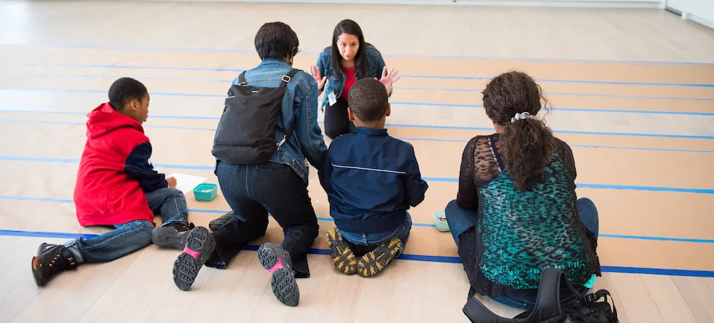 Four young visitors preparing to participate in artmaking activity with gallery educator 